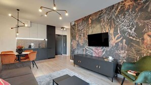 Uma sala de estar moderna com sofá, mesa de centro, TV na parede e área de jantar com cadeiras e mesa.