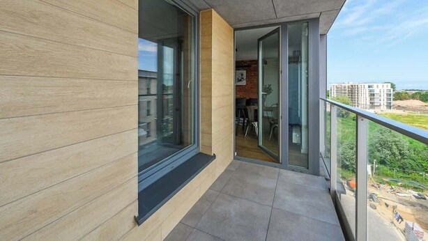Een modern balkon met glazen deuren, uitzicht op de stad en een eethoek die zichtbaar is door het glas.