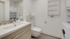 Een moderne badkamer met een wastafel, toilet en een wasmachine.