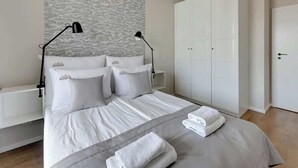 Een keurig opgeruimde slaapkamer met een bed, twee nachtkastjes, een kledingkast en een lamp.