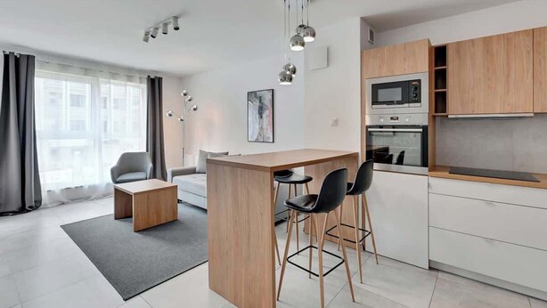Eine moderne Küche mit einer zentralen Kochinsel, Barhocker und integrierten Geräten.