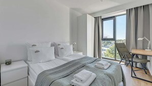 Ein modernes Hotelzimmer mit einem großen Bett, einem Schreibtisch und Blick auf die Stadt.