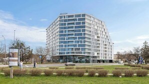 Ein modernes Gebäude mit flachem Dach, mehreren Etagen und einer markanten Beschilderung oben.