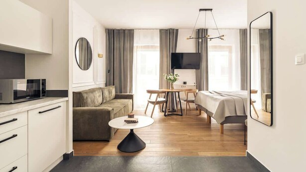 Ett modernt hotellrum med ett litet kök, en soffa, ett matbord och en säng.