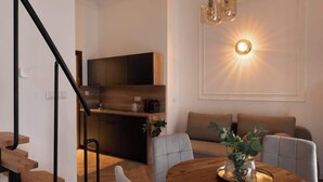 Un interior moderno con una escalera, un comedor con una mesa de madera y una cocina al fondo.