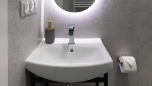 A bathroom with a white sink, a mirror, and a towel rack. - L23 Boutique 13B | City Center (Kraków)