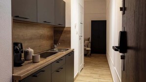 A narrow kitchen with dark cabinets, a wooden countertop, and a coffee machine. - L23 Boutique 13B | City Center (Kraków)