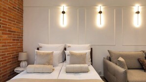 A hotel room with a bed, two bedside tables, a sofa, and wall-mounted lighting. - L23 Boutique 13B | City Center (Kraków)