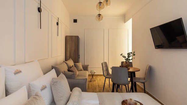 A modern hotel room with a bed, sofa, dining area, and a TV mounted on the wall. - L23 Boutique 13B | City Center (Kraków)