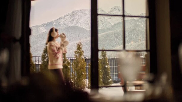 Ein Zimmer mit großem Fenster mit Blick auf einen verschneiten Berg.