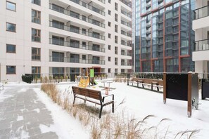 A multi-story building with balconies, a snow-covered ground, and outdoor seating. - Towarowa Square | Balcony & Parking (Warszawa)