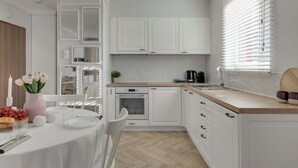 Una cocina moderna con armarios blancos, un comedor con mesa redonda y una ventana con persianas.