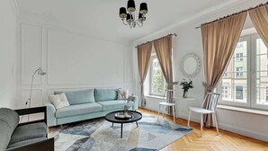 En stue med sofa, rundt sofabord, stol og lysekrone.