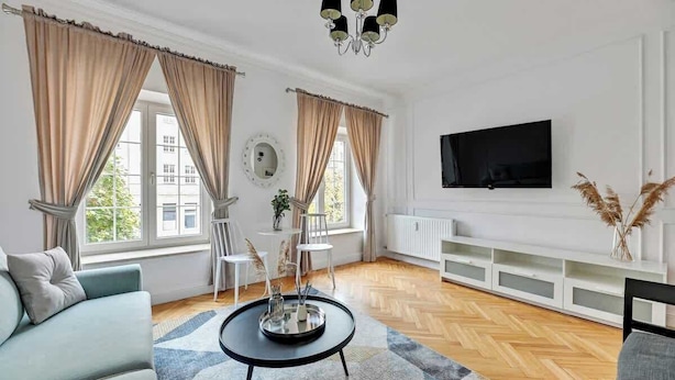 En moderne stue med sofa, sofabord, fjernsyn og pejs.