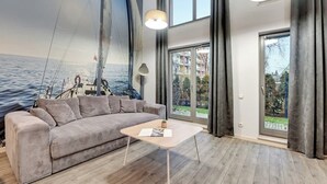 Ein modernes Wohnzimmer mit einem großen Fenster, einem Sofa, einem Couchtisch und einer Wandmalerei mit einem Segelboot.