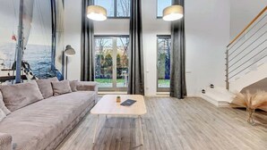 Ein modernes Wohnzimmer mit großem Fenster, einer Couch, einem Couchtisch und einer Treppe.