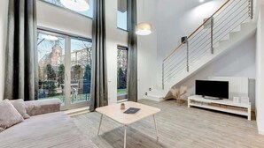 Ein modernes Wohnzimmer mit einer Couch, einem Couchtisch, einem Fernseher und einer Treppe.