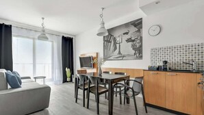 Ein modernes Wohnzimmer mit einer Couch, einem Esstisch, Stühlen und einer Küchenzeile mit Spüle und Schränken.