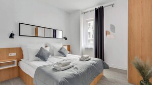 Ein modernes Schlafzimmer mit einem Bett, Nachttischen, einem Spiegel und einem Fenster mit Vorhängen.