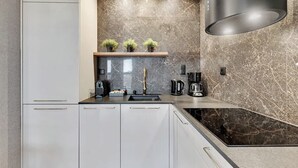 Una cucina moderna con mobili bianchi, un piano di lavoro nero, un fornello integrato e uno schienale in marmo.