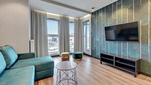 Un soggiorno moderno con un'ampia televisione a schermo piatto, un divano, un tavolino rotondo e una parete decorata con motivi.