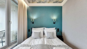 Una camera d'hotel con un letto grande, due lampade a parete, una finestra con vista e un balcone.