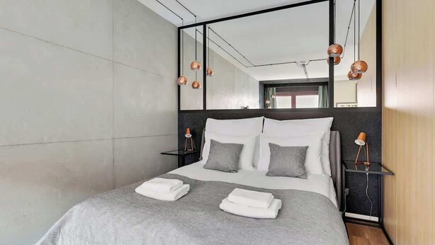 A modern hotel room with a large bed, a mirror, and bedside lamps. - Nº 75 | Pool, SPA & Gym (Gdańsk)