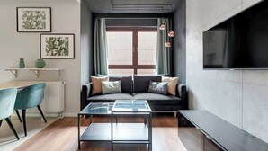 A modern living room with a sofa, a glass coffee table, a TV, and artwork on the wall. - Nº 75 | Pool, SPA & Gym (Gdańsk)