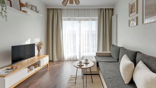 A modern living room with a flat-screen TV, a sofa, a coffee table, and a large window with curtains. - Nadmotławie 45 | Riverside | Sauna & Gym (Gdańsk)