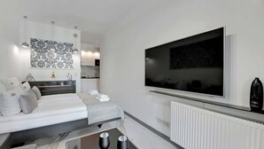 A modern hotel room with a bed, a TV, a marble countertop, and a wall-mounted artwork. - Granaria B23 | Perfect Location | Old Town (Gdańsk)