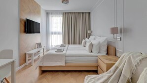 Ein modernes Hotelzimmer mit Bett, Nachttisch, Lampe und einem an der Wand befestigten Fernseher.