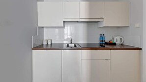 Eine moderne Küche mit weißen Schränken, einer Edelstahlspüle und einer Holzausziehtafel.