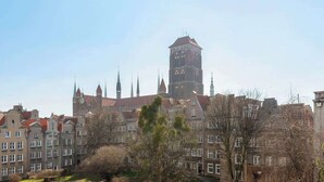 Um edifício histórico com uma torre do relógio imponente, rodeado por arquitetura europeia tradicional.