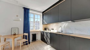 Uma cozinha moderna com armários escuros, bancada de madeira e uma janela com cortinas azuis.