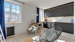 Uma cozinha moderna com armários escuros, bancada de madeira e janela com cortinas azuis.