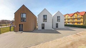 A modern building with a wooden facade, a white building with a pitched roof, and a yellow building with red roofs. - Stodoła 1 | Nad Morzem | Jastrzębia Góra (Jastrzębia Góra)