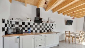 Eine moderne Küche mit kariertem Fliesenspiegel, weißen Schränken, einer eingebauten Mikrowelle und einem Essbereich mit Holztischen und -stühlen.