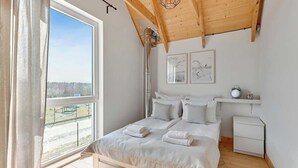 Ein Schlafzimmer mit Bett, Nachttisch, Fenster und einem Kunstwerk an der Wand.