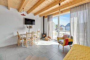 Ein modernes Wohnzimmer mit Holzboden, Kamin, Essbereich und Sofa.