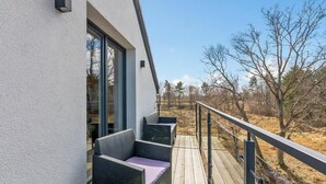 A modern building with a balcony featuring wicker furniture and a glass door. - Dębki 6 | Rodzinny Apartament | Nad Morzem (Dębki)