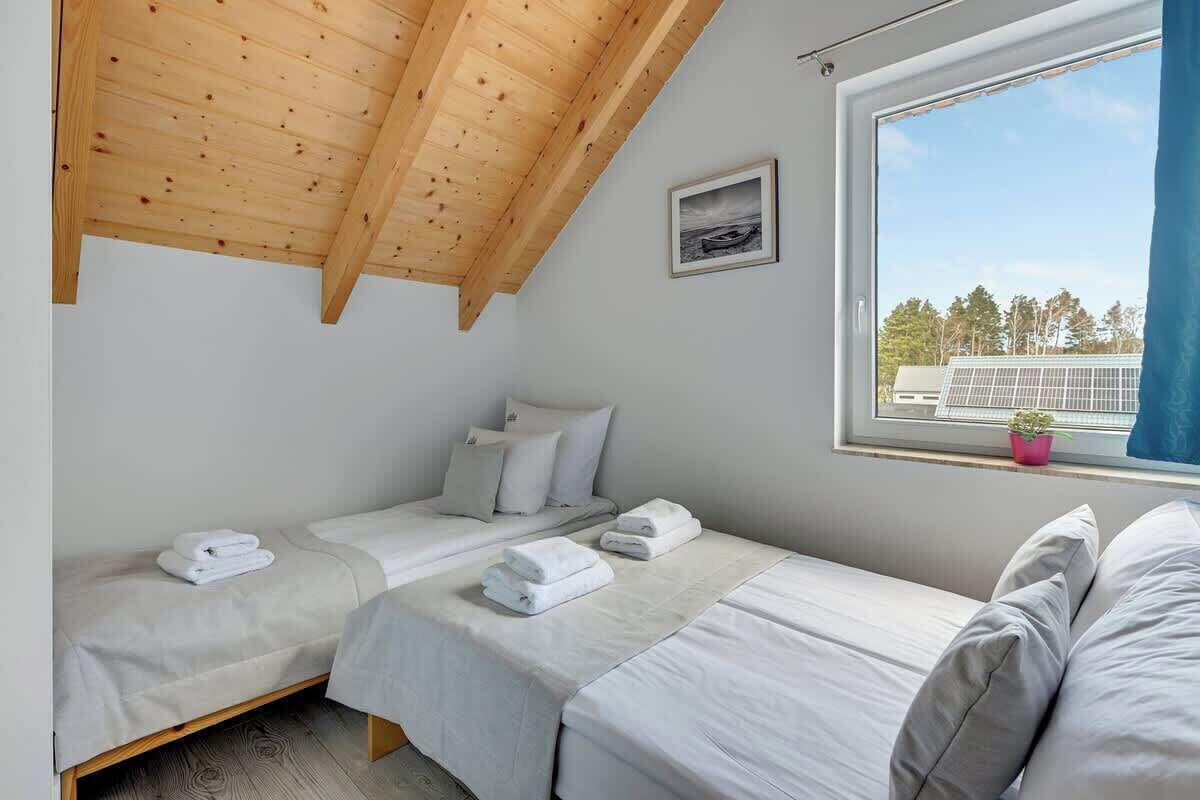 Un dormitorio con dos camas, una ventana con vistas y un techo con vigas de madera.