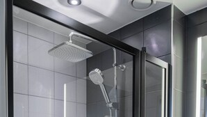 A modern bathroom with a glass-enclosed shower, a white sink, and a large mirror. - Citybox Tromsø (Tromsø)