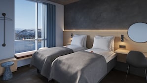 A modern hotel room with two beds, a large window with a view of mountains, a round mirror on the wall, and a small round table. - Citybox Tromsø (Tromsø)