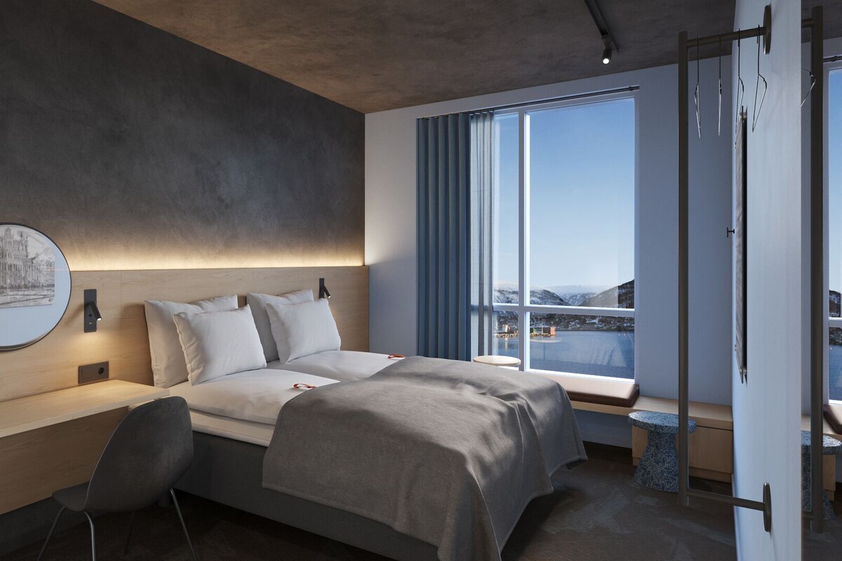 Ein modernes Schlafzimmer mit Bett, Nachttisch, Stuhl und einem großen Fenster mit Blick.
