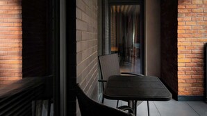 A narrow corridor with brick walls, a glass door, and a small table with a chair. - Wawrzyńca 59 | Perfect for Families (Kraków)