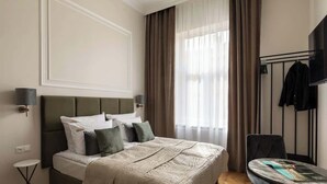 Een hotelkamer met een bed, een ronde tafel, een stoel, een televisie en een kapstok.