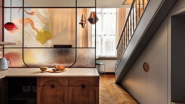 Een moderne keuken met een houten aanrecht, een glazen scheidingswand en uitzicht op de stad door grote ramen.