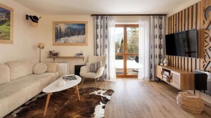 Ein Wohnzimmer mit einer Couch, einem Couchtisch, einem Sessel, einem Fernseher und einem Holz-TV-Schrank.