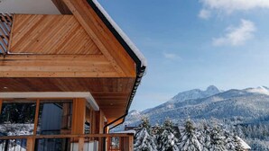 A wooden cabin with a balcony overlooking a snowy mountain landscape.
