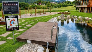 A wooden dock extending into a pond with a sign indicating a swimming area.